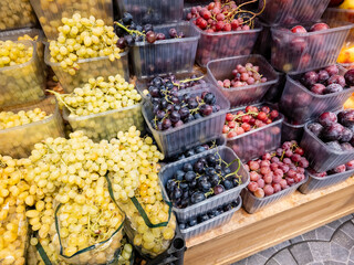 Variety of fresh grapes displayed in containers at a market