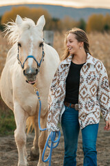 Fototapeta premium Young woman having great time with a horse in field on autumn season. sunset hour