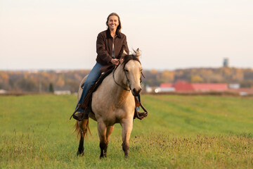 Young woman having great time with a horse in field on autumn season. sunset hour