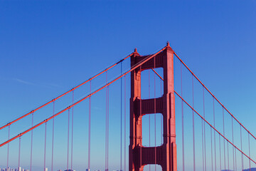 Golden Gate Bridge with San Francisco Skyline in the Distance – Iconic Red Steel Structure Framing the City’s Modern Architecture Under a Clear Blue Sky, Captured in Vibrant California Travel Photo