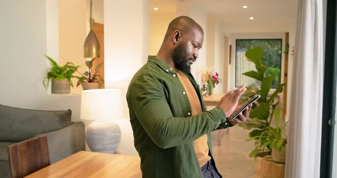 African American man at dining table annotating content with stylus on tablet, looking up
