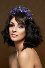 Fototapeta premium Studio portrait for a beauty advertising campaign. The photo shows a young woman with dark hair. She's barely wearing makeup, her lips are shiny, and her eyes express confidence and calm.