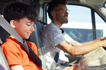 family trips and vacations concept. man driving and teenage boy looking at road map