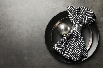 Christmas setting with plates, napkin and bauble on grey table, top view. Space for text
