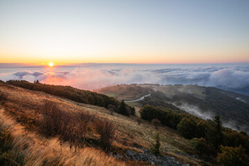 Fototapeta premium Stimmungsvoller Sonnenaufgang über dem Nebelmeer in den Vogesen mit Blick vom Großen Belchen. Am Horizont die tiefstehende Sonne, die Schwarzwaldgipfel und die Alpen.
