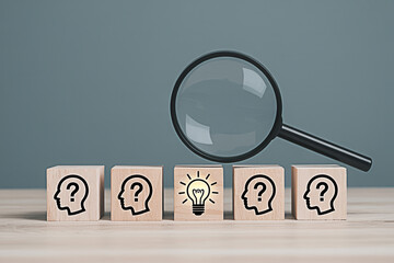 Finding solutions and ideas concept with magnifying glass light bulb and question mark wooden blocks