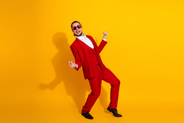 Energetic man in red suit dancing against bright yellow background creating a playful stylish mood for fashion entertainment and promo campaigns