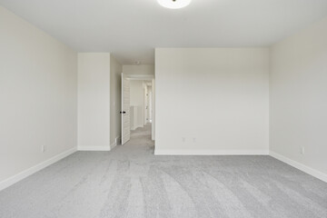 Large, empty room with a white door and a white wall
