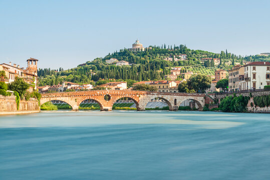 Die r&ouml;mische Ponte Pietra &uuml;ber dem Flu&szlig; Etsch in der Altstadt von Verona vor mediterraner Landschaft in der Morgensonne, Venetien, Italien