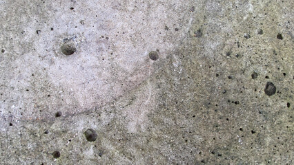 A full-frame, close-up texture of rough gray concrete or cement with visible pores, air bubbles, and natural surface imperfections.