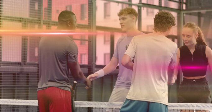 Friends converging on padel court post match exchanging rackets and bumping fists before leaving