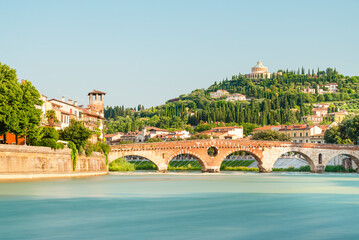 Die römische Ponte Pietra über dem Fluß Etsch in der Altstadt von Verona vor mediterraner Landschaft in der Morgensonne, Venetien, Italien