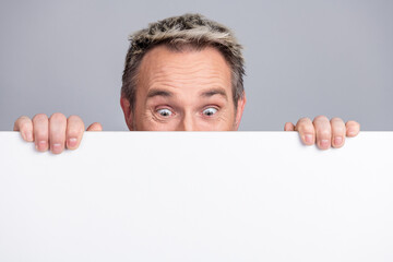 Mature man behind white board showcasing creativity, advertising concepts or corporate promotion ideas with a playful attitude