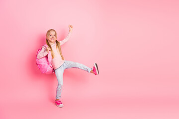 Cheerful little girl posing with trendy backpack on vivid pink background showing joyous gesture