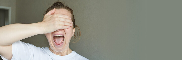 Surprised caucasian female shields eyes with hand, expressing joy and laughter.