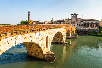 Fototapeta premium Die römische Ponte Pietra über dem Fluß Etsch in der Altstadt von Verona leuchtet in der Abendsonne, Venetien, Italien