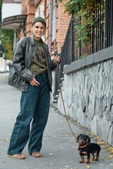 Woman walking a dachshund dog on a leash in an urban setting
