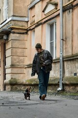 Person walking a dachshund dog on a leash down a city street