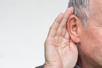 Elderly man with symptom of hearing loss, or deaf person with hand gesture to listen