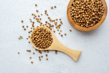 wooden bowl and spoon with coriander seeds on white background