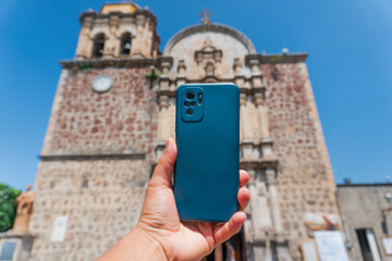 Naklejka premium Hand holding smartphone capturing historic church in tequila, mexico