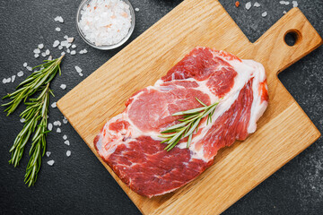 Raw beef steak with rosemary and spices on wooden board