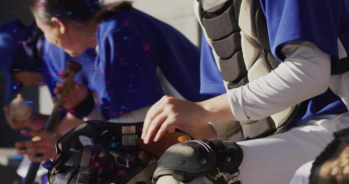 Baseball catcher reaching down gripping helmet in dugout lifting mask and securing straps pre-game