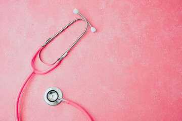 Pink stethoscope on pink background, flat lay medical tool