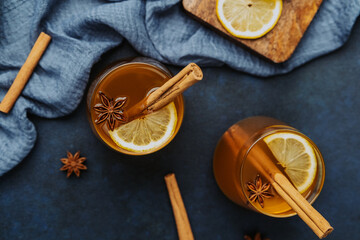 Warm spiced drink with cinnamon sticks, lemon slices, and star anise on dark surface © reddish