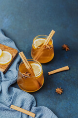Warm spiced drink in glasses with cinnamon sticks, star anise, and lemon slices