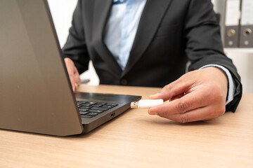 Businessman hand plugging pen drive on laptop at office