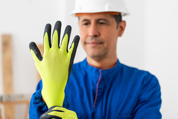 Construction worker putting protective yellow glove before work in a house under reform