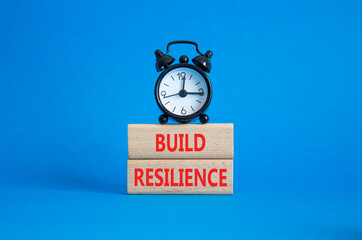 Build resilience symbol. Wooden blocks with words Build resilience. Beautiful blue background with alarm clock. Business and Build resilience concept. Copy space.
