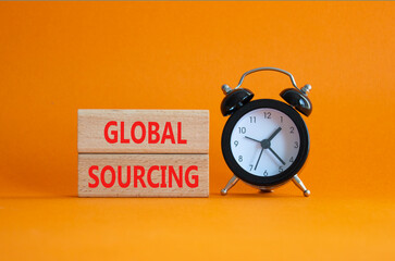 Global Sourcing symbol. Wooden blocks with words Global Sourcing. Beautiful orange background with alarm clock. Business and Global Sourcing concept. Copy space.
