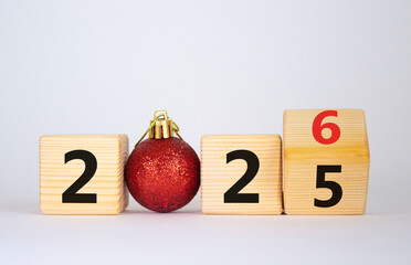 2026 New Year symbol. Businessman turns wooden cube and changes Year 2025 to 2026. Beautiful white background with christmas ball. Copy space. Business and 2026 happy new year concept