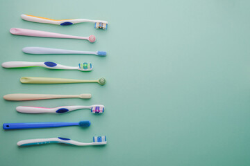 Collection of colorful toothbrushes lying on a pastel background, top view