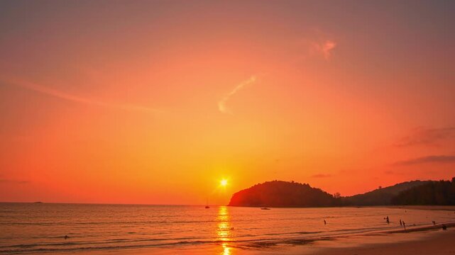 Time lapse A golden tropical sunset paints the sky with vibrant hues, casting shimmering reflections across the calm ocean waves. Picturesque Tropical Sky at Sunset at Kala island Layan beach Phuket