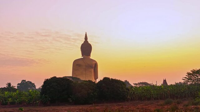 scenery sunset behind the great golden Buddha landmark of Thailand at wat Muang Ang Thong Thailand. 
The largest Buddha statue in the world Surrounded by rice fields.
colorful sky background. 