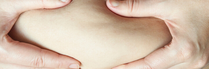 Close-up of hands pinching skin on a caucasian adult arm highlighting skin texture and elasticity.