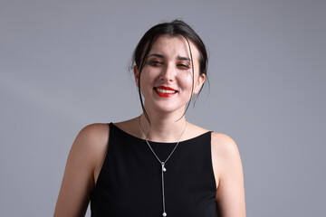 Woman with smeared mascara in dress laughing through tears on grey background