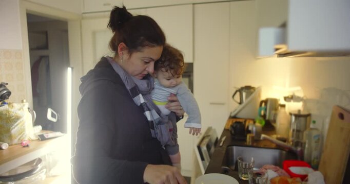 Mother cooking while holding baby, multitasking household work and childcare, expressing calm focus, patience, and the emotional strength of daily motherhood at home