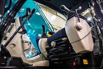 Inside the modern cab of a powerful excavator, featuring ergonomic control joysticks, a comfortable operator seat, and tinted windows. Ready for heavy construction work and industrial operations. © dizfoto1973