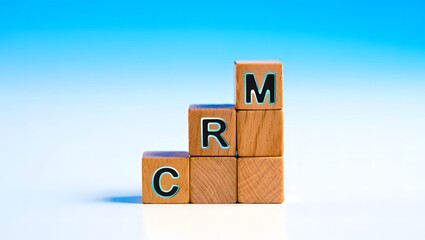 Wooden blocks stacked with letters CRM representing Customer Relationship Management concept against blue and white gradient background