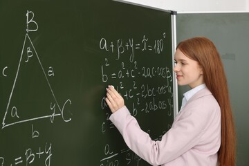 Back to school. Student doing math on chalkboard indoors
