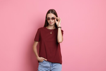 Woman wearing burgundy t-shirt on pink background. Mockup for design