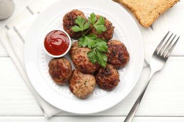 Delicious patties with parsley and ketchup served on white wooden table, flat lay