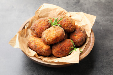 Delicious patties with rosemary in bowl on grey textured table, closeup