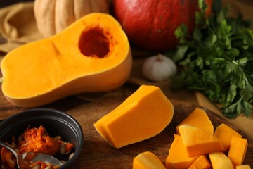 Fresh pumpkins, seeds and spices on wooden table, closeup
