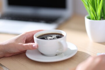 Woman having coffee break at wooden table, closeup