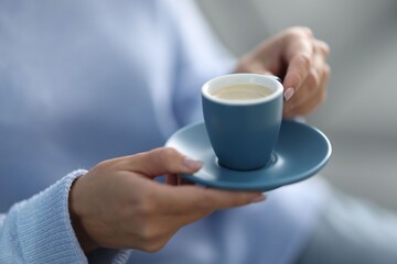 Woman having coffee break on blurred background, closeup
